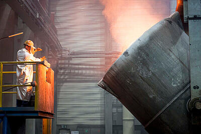 Ein Mitarbeiter bedient die Steuerung einer der großen Schmelzkessel.