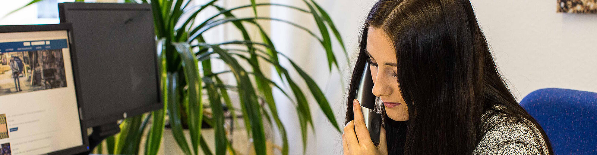 Eine Frau führt ein Telefonat am Schreibtisch.