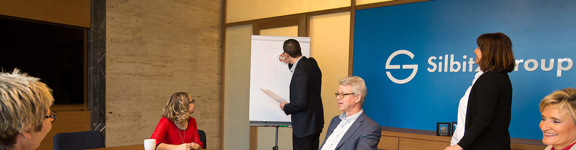 Silbitz Group Einkaufsorganisation Mehrere Personen sitzen bei einem Meeting zusammen und besprechen diverse Themen.