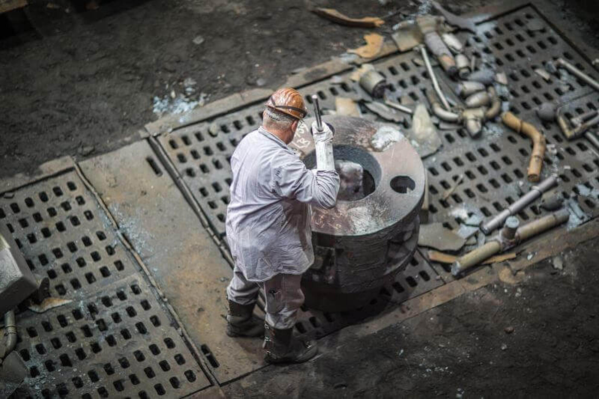 Silbitz Group Stahlguss Herstellung Ein Mitarbeiter säubert eines der Gussteile nach der Herstellung.